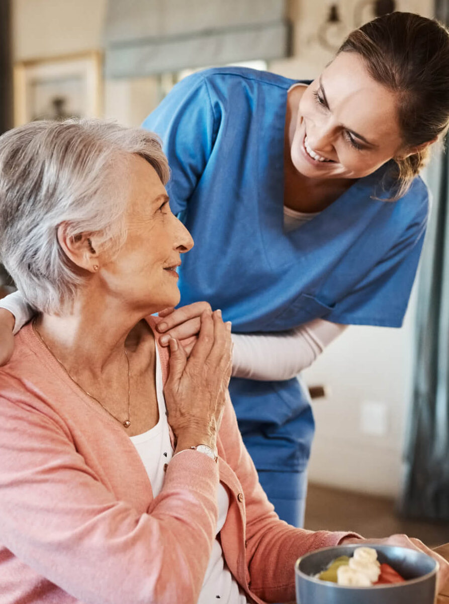 Freundliche Pflegerin spricht und kümmert sich liebevoll um Patientin