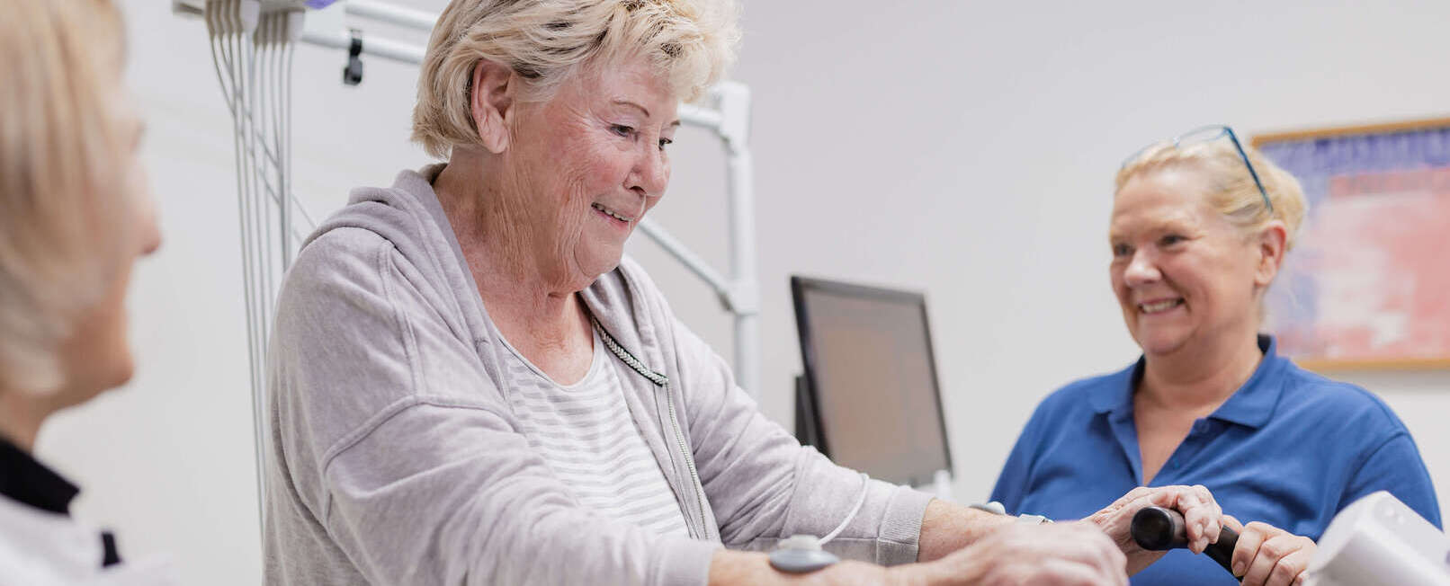 Pflegerin zeigt Patientin ein Gerät zum trainieren