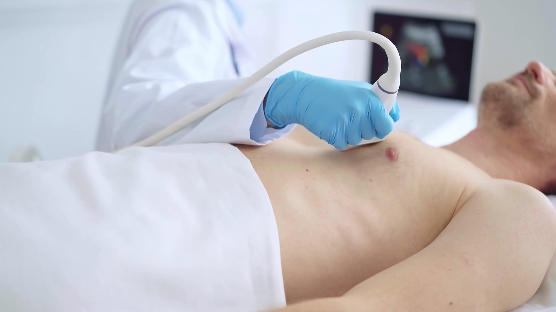 Doctor woman wearing blue medical gloves performing breast and heart ultrasound exam on man patient. Medicine service, cardiology